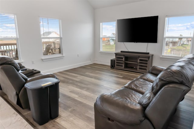 living room featuring lofted ceiling, plenty of natural light, baseboards, and wood finished floors