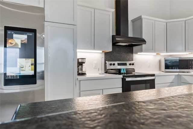 kitchen with appliances with stainless steel finishes, white cabinetry, and wall chimney exhaust hood