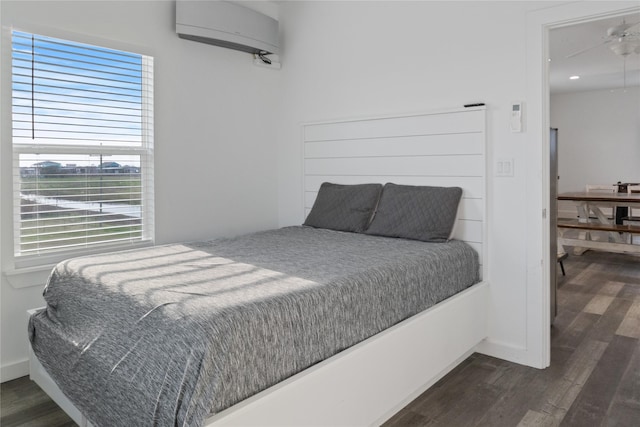 bedroom featuring baseboards, dark wood-style flooring, and a wall mounted air conditioner