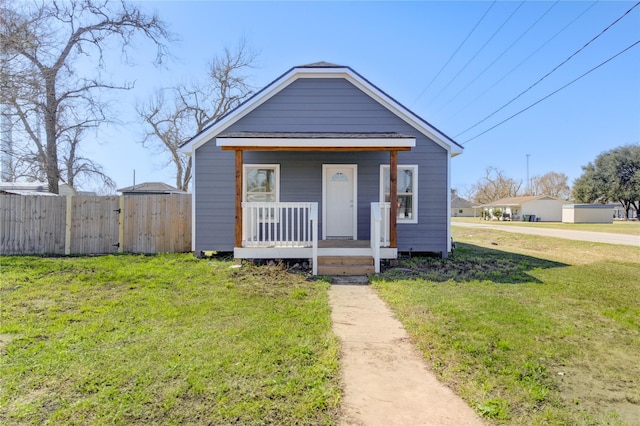 view of front of property featuring a porch, fence, and a front lawn