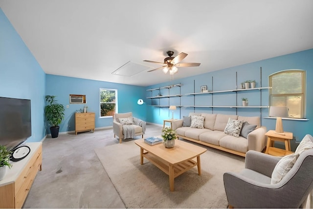 living area with attic access, baseboards, ceiling fan, and concrete flooring