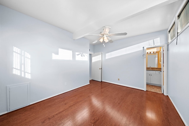 unfurnished bedroom with baseboards, hardwood / wood-style flooring, ceiling fan, beamed ceiling, and ensuite bathroom