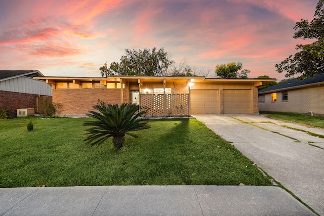 mid-century inspired home with concrete driveway, brick siding, a lawn, and an attached garage