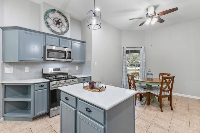 kitchen featuring light tile patterned floors, light countertops, decorative backsplash, appliances with stainless steel finishes, and a kitchen island