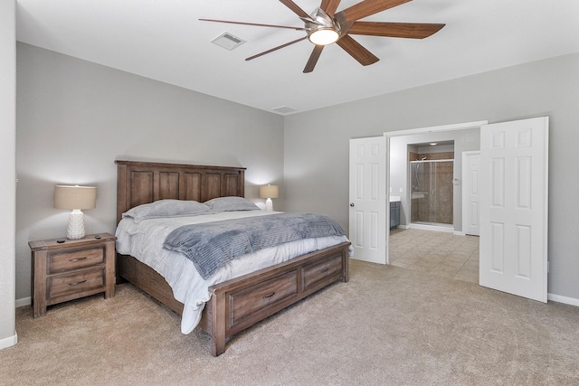 bedroom featuring ceiling fan, light colored carpet, visible vents, baseboards, and ensuite bath