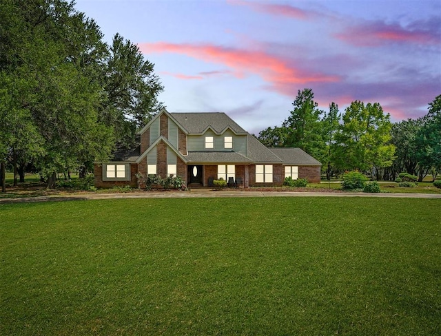 view of front of home featuring brick siding and a yard