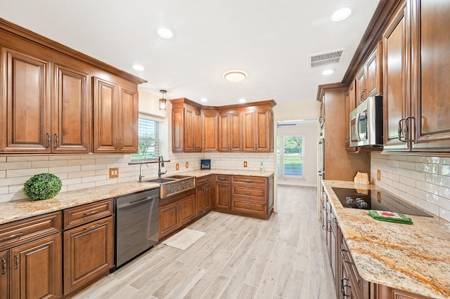 kitchen with stainless steel appliances, a wealth of natural light, visible vents, brown cabinetry, and a sink