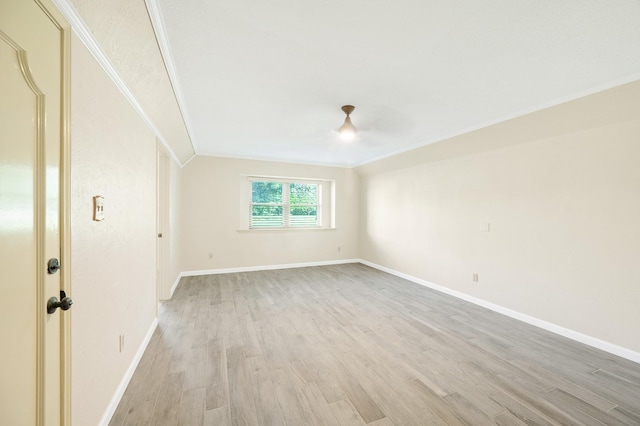 empty room featuring ornamental molding, light wood-type flooring, and baseboards