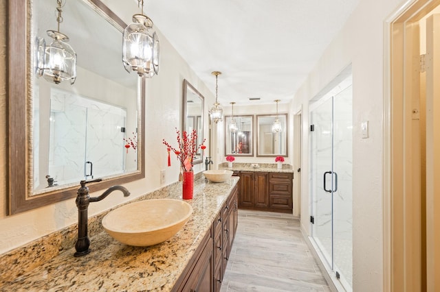 full bathroom with double vanity, a marble finish shower, and a sink