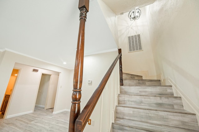 staircase with baseboards, visible vents, and wood finished floors