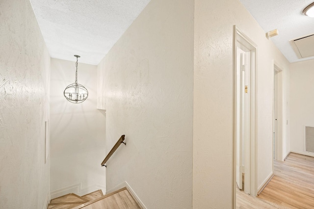 stairs with a textured ceiling, wood finished floors, and a textured wall