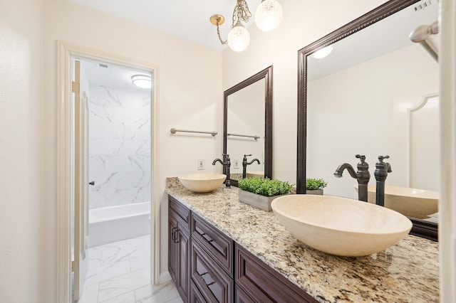 full bathroom with marble finish floor, double vanity, shower / bath combination, and a sink