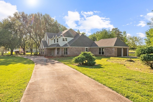 view of front of property with a garage, brick siding, driveway, and a front lawn