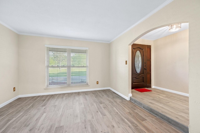 foyer with light wood finished floors, baseboards, arched walkways, and crown molding