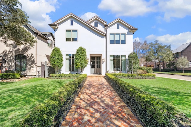 mediterranean / spanish home with stucco siding, a tile roof, and a front yard