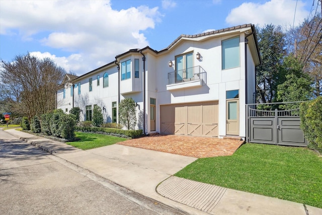 view of front of property with driveway, a balcony, a front lawn, and stucco siding