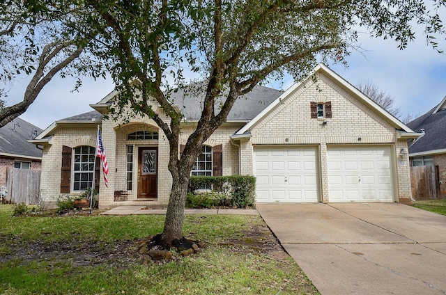 view of front of house featuring brick siding, driveway, an attached garage, and fence