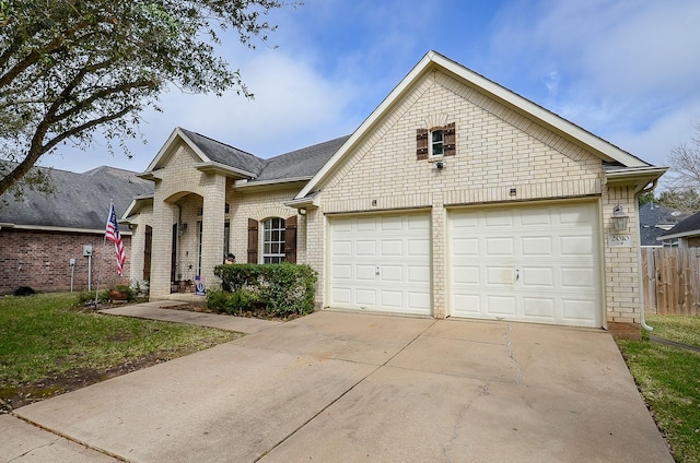 view of front of home with driveway, a garage, roof with shingles, fence, and brick siding