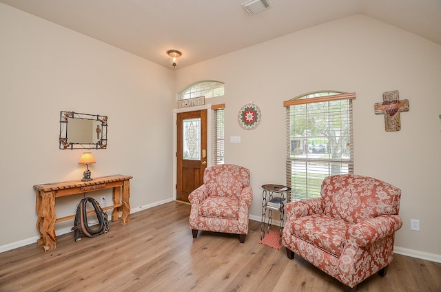 sitting room with lofted ceiling, baseboards, visible vents, and light wood-style floors