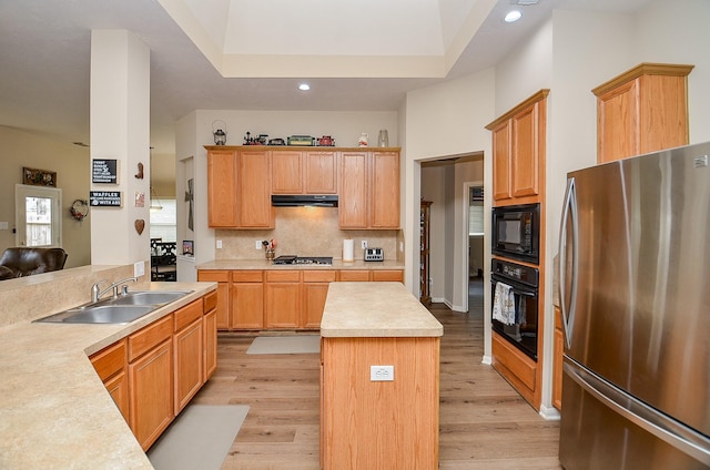 kitchen featuring backsplash, under cabinet range hood, light countertops, black appliances, and a sink