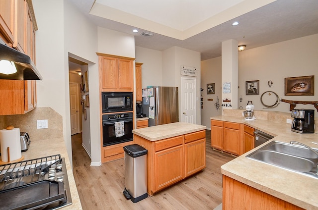 kitchen featuring a sink, visible vents, light wood-style floors, a center island, and black appliances