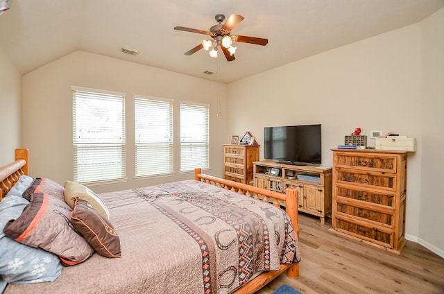 bedroom featuring light wood-style floors, lofted ceiling, visible vents, and a ceiling fan