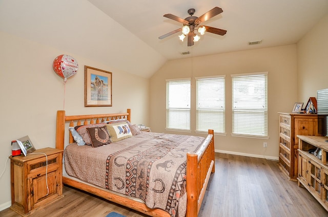 bedroom with lofted ceiling, baseboards, visible vents, and wood finished floors