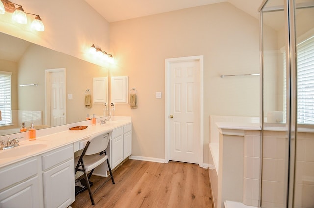 full bath with lofted ceiling, wood finished floors, a sink, and a bath