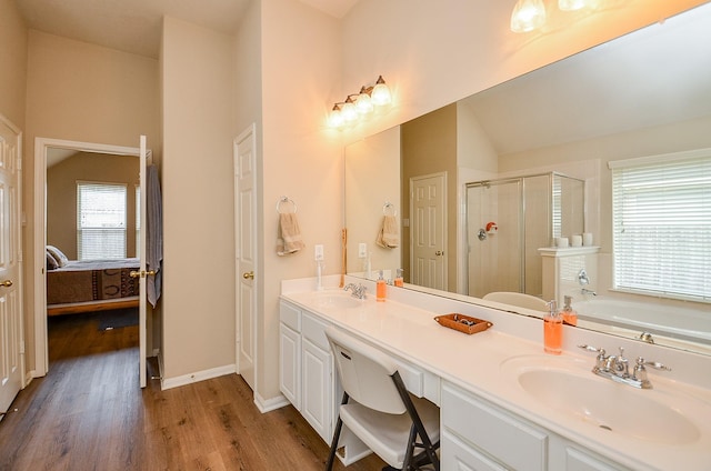 ensuite bathroom with connected bathroom, wood finished floors, a sink, a shower stall, and double vanity