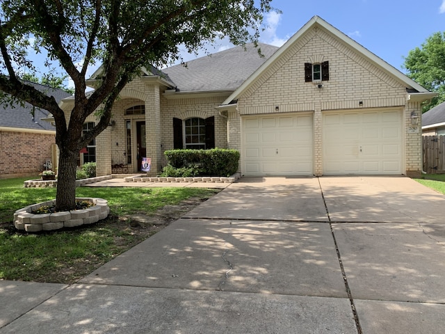 view of front of home with driveway, roof with shingles, an attached garage, and brick siding