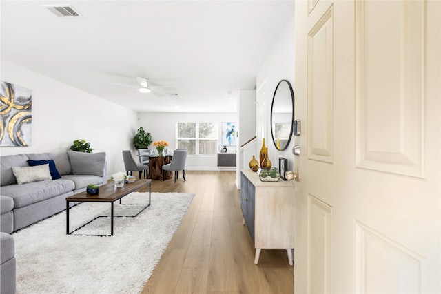 living room with a ceiling fan, light wood-type flooring, and visible vents