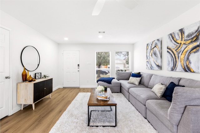 living room featuring baseboards, visible vents, wood finished floors, and recessed lighting