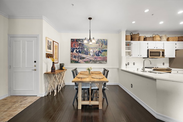 dining area featuring dark wood-style floors, ornamental molding, a chandelier, and baseboards