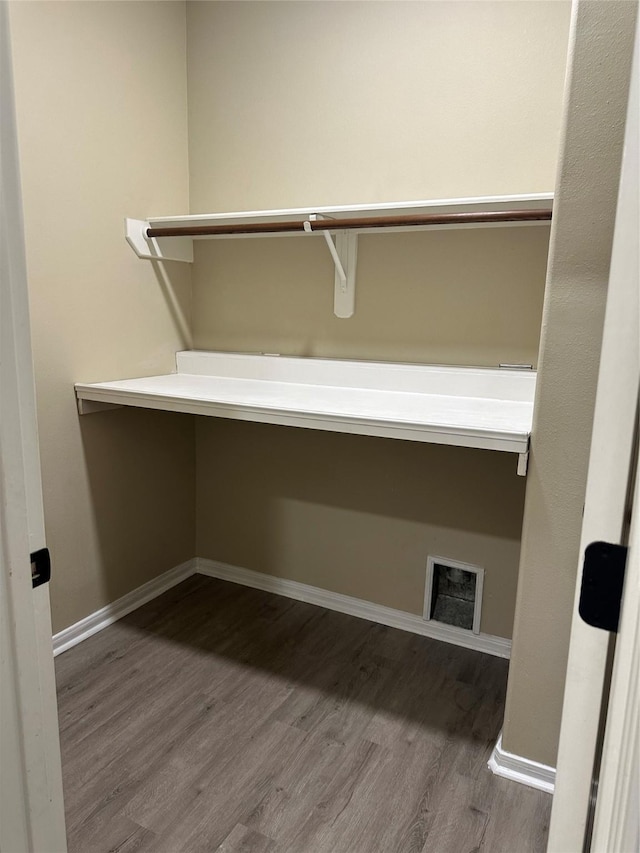 interior space with visible vents, built in desk, and wood finished floors