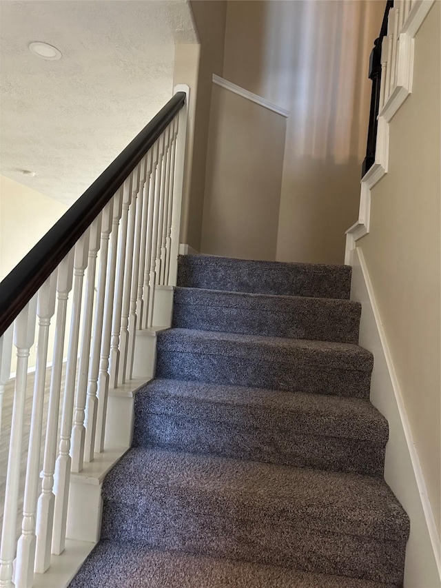 staircase featuring a textured ceiling