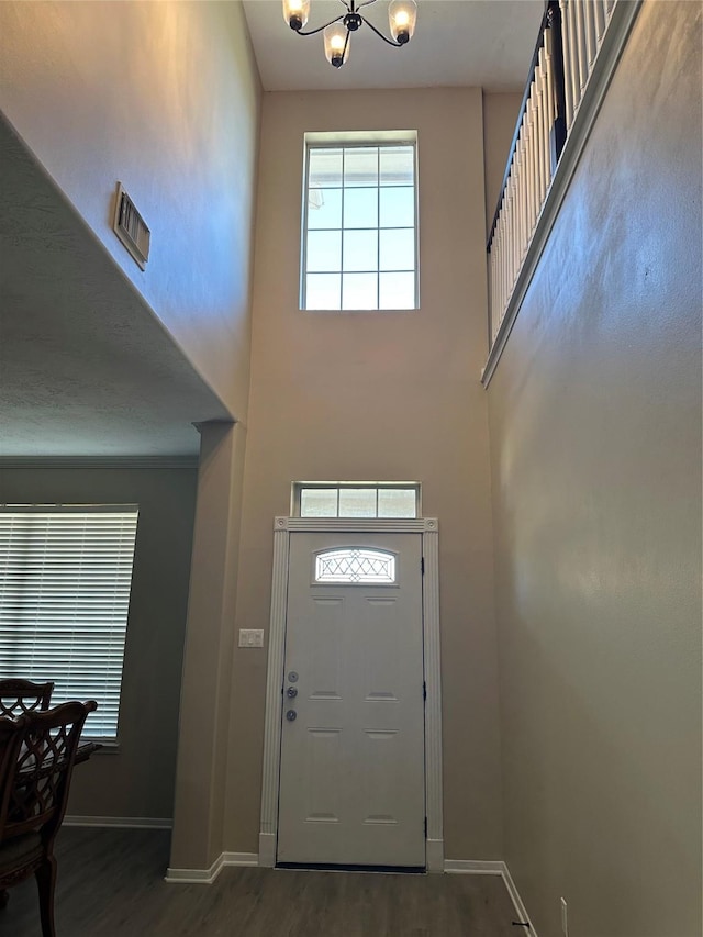 foyer entrance featuring baseboards, a high ceiling, and wood finished floors