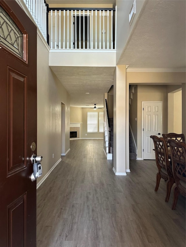 foyer entrance featuring a tile fireplace, stairway, baseboards, and wood finished floors