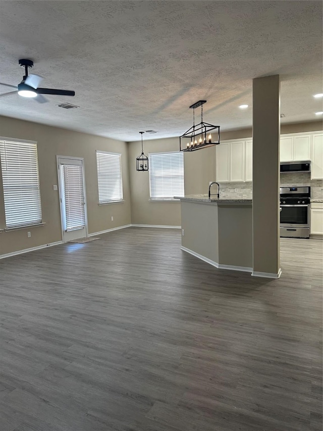 interior space with stainless steel appliances, dark wood-type flooring, a sink, white cabinetry, and decorative backsplash