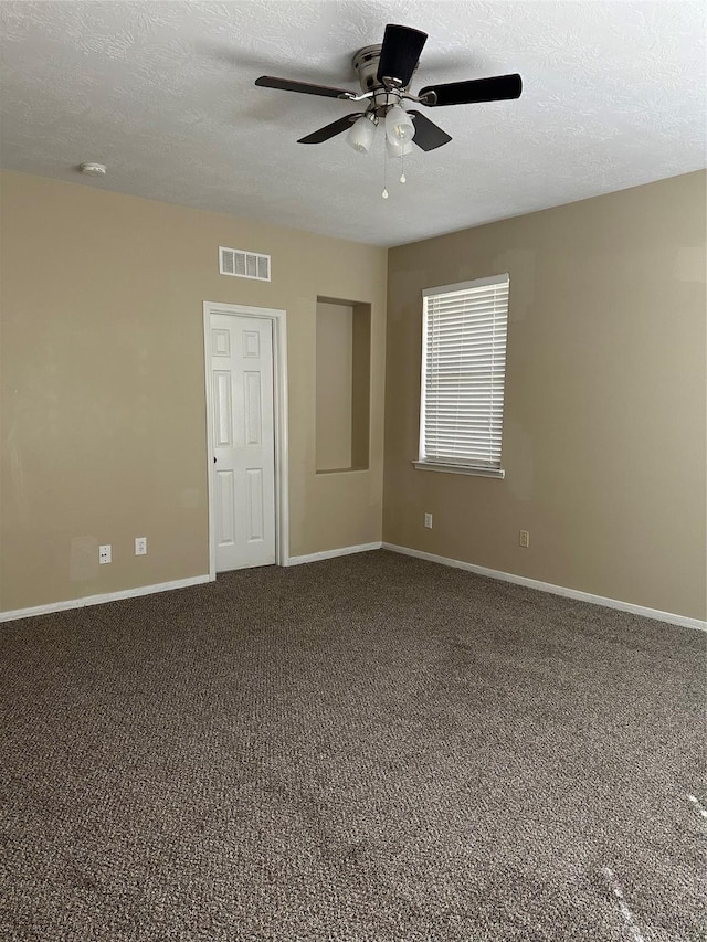 carpeted empty room featuring visible vents, ceiling fan, a textured ceiling, and baseboards