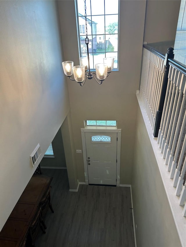 foyer with stairway, baseboards, a chandelier, and wood finished floors