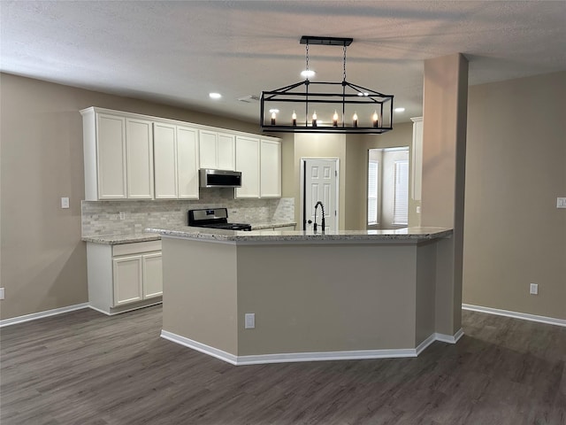 kitchen featuring stainless steel microwave, decorative backsplash, white cabinetry, and range with gas stovetop