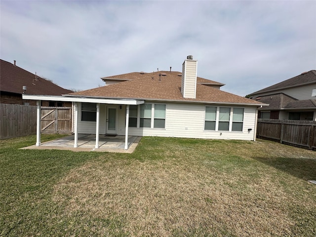 rear view of house featuring a patio area, a fenced backyard, a chimney, and a yard