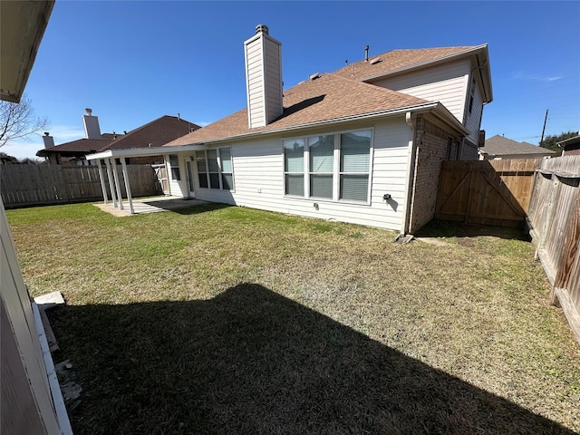 rear view of house with a fenced backyard, a lawn, brick siding, and a patio