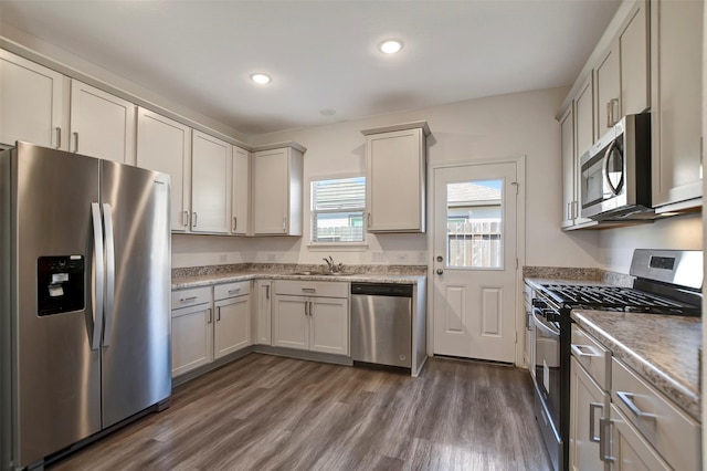 kitchen featuring dark wood-style flooring, stainless steel appliances, a sink, and recessed lighting