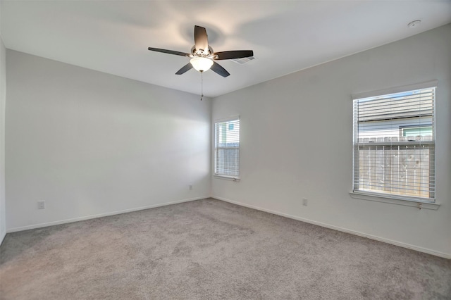 carpeted empty room with a ceiling fan, visible vents, and baseboards