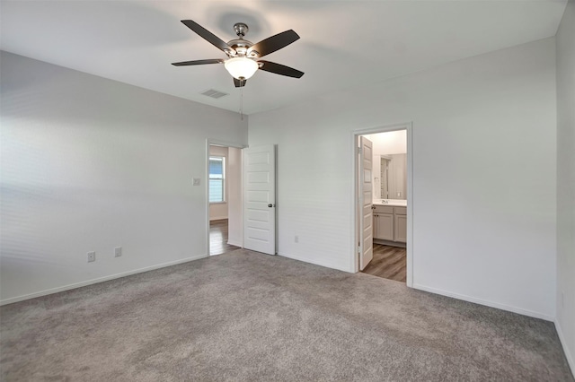 unfurnished bedroom featuring light carpet, baseboards, visible vents, ceiling fan, and ensuite bathroom