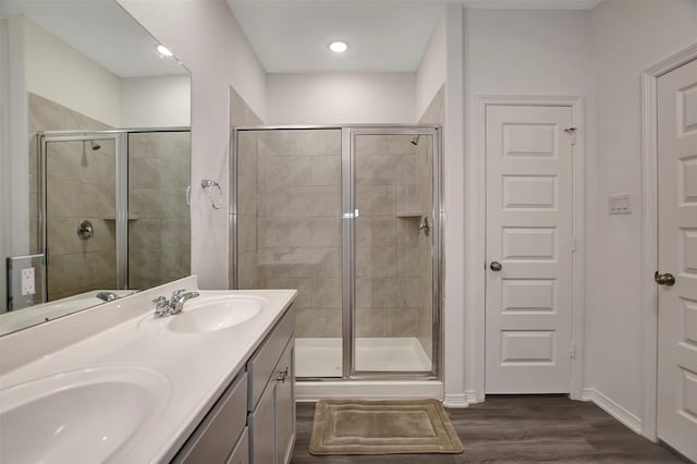 bathroom with wood finished floors, a sink, and a shower stall