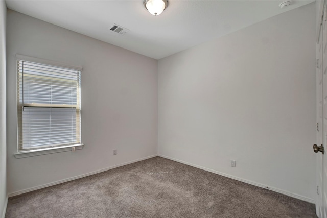 unfurnished room with carpet floors, visible vents, and baseboards