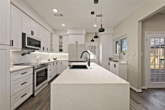 kitchen with a sink, visible vents, appliances with stainless steel finishes, backsplash, and open shelves