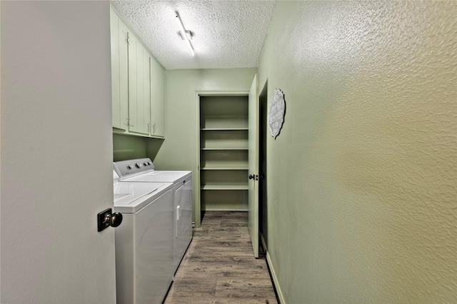 clothes washing area featuring cabinet space, a textured wall, wood finished floors, independent washer and dryer, and a textured ceiling